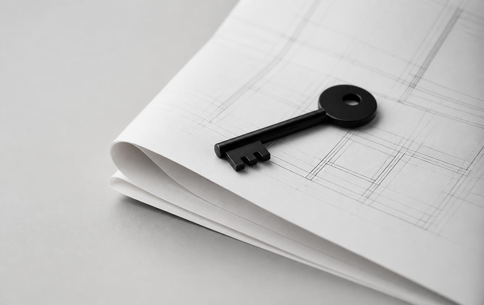 A black key resting on a folded architectural blueprint