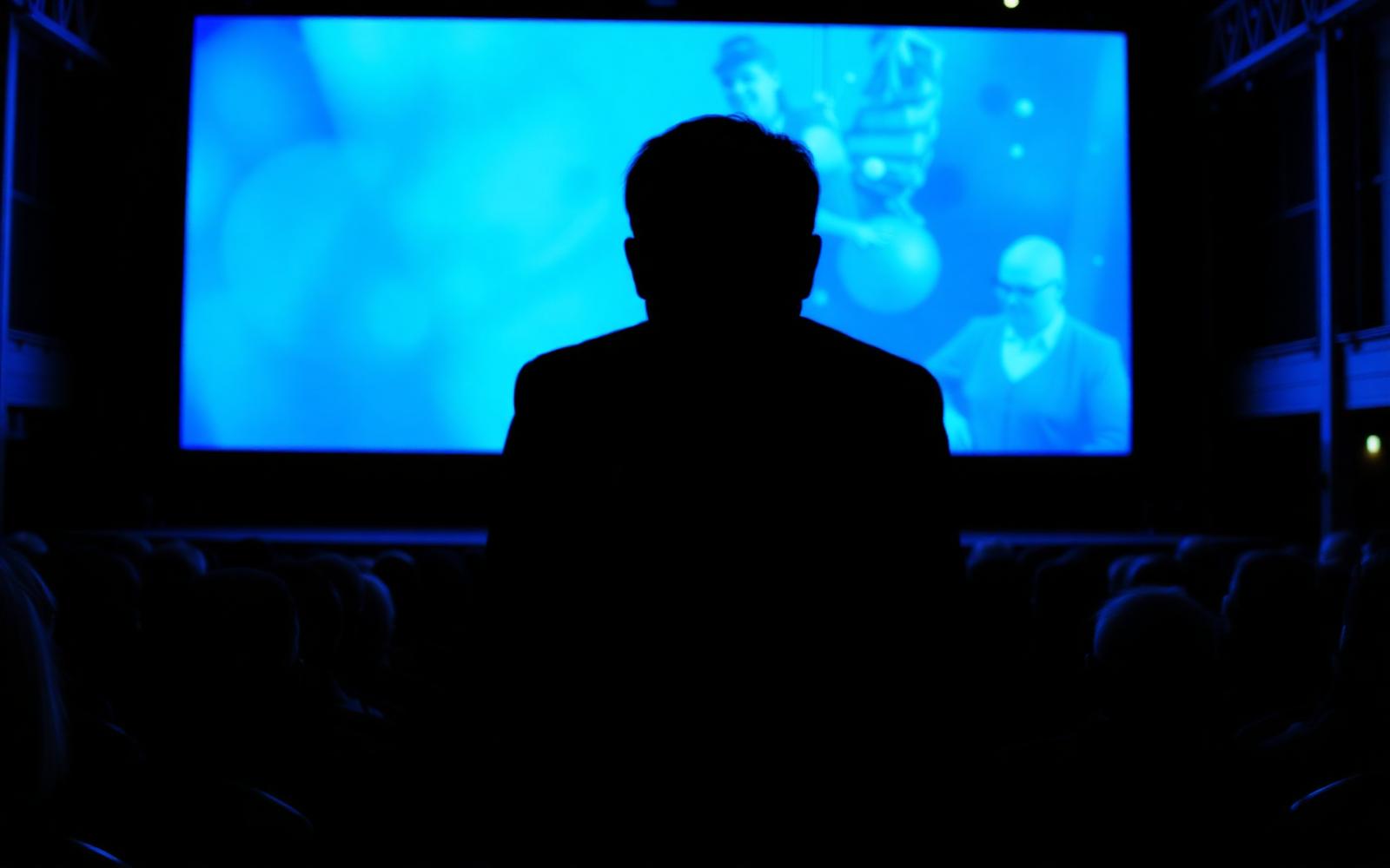 Conference stage with a speaker silhouette against a blue screen